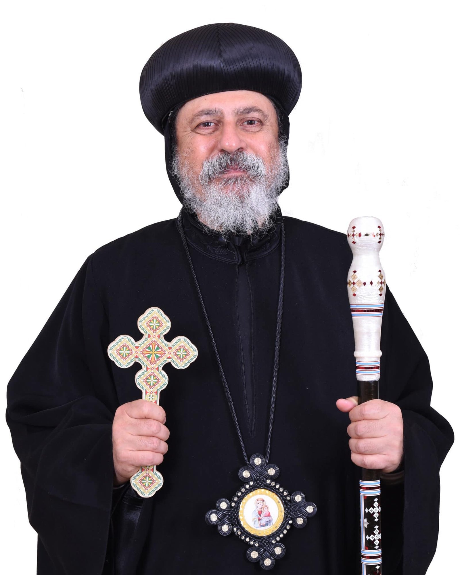 Bishop Daniel in traditional Coptic Orthodox vestments with white beard, holding a cross and ceremonial staff
